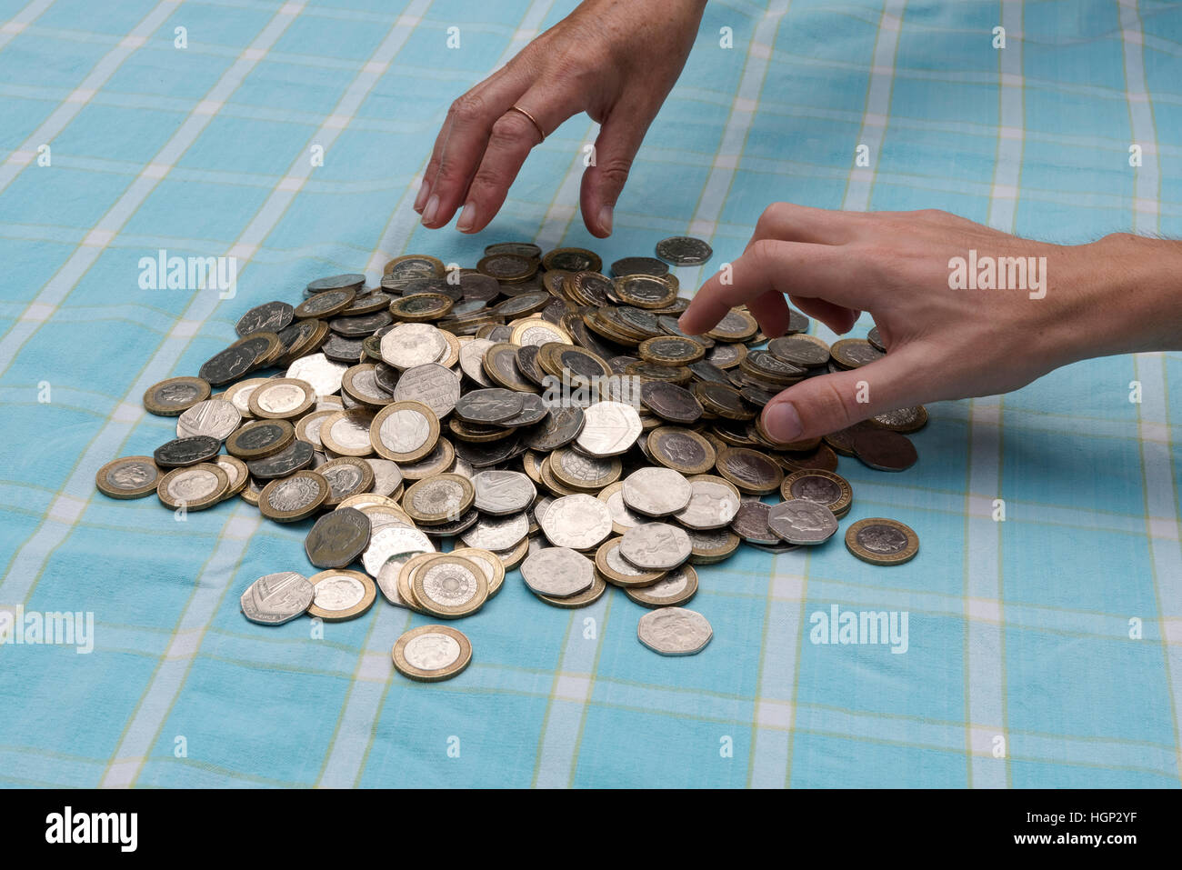 Deux mains saisissant à une pile de £2 et 50 pence de monnaie. Banque D'Images