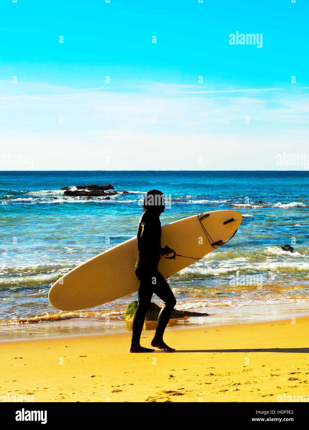 Silhouette d'un surfeur sur la plage dans une journée ensoleillée Banque D'Images