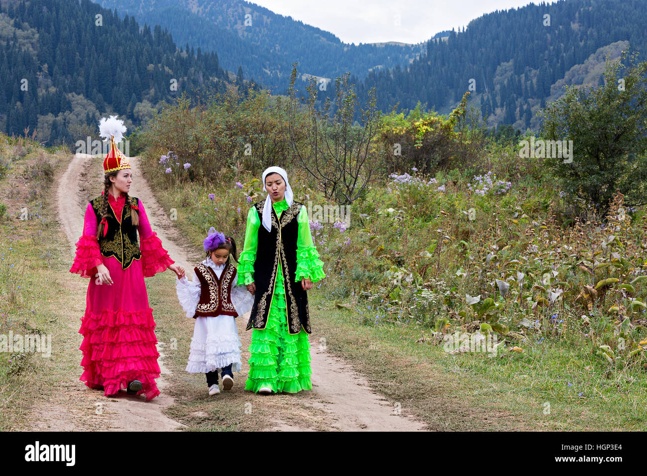 Les femmes kazakhes en costumes nationaux et une fille marchant dans la nature à Almaty, Kazakhstan Banque D'Images