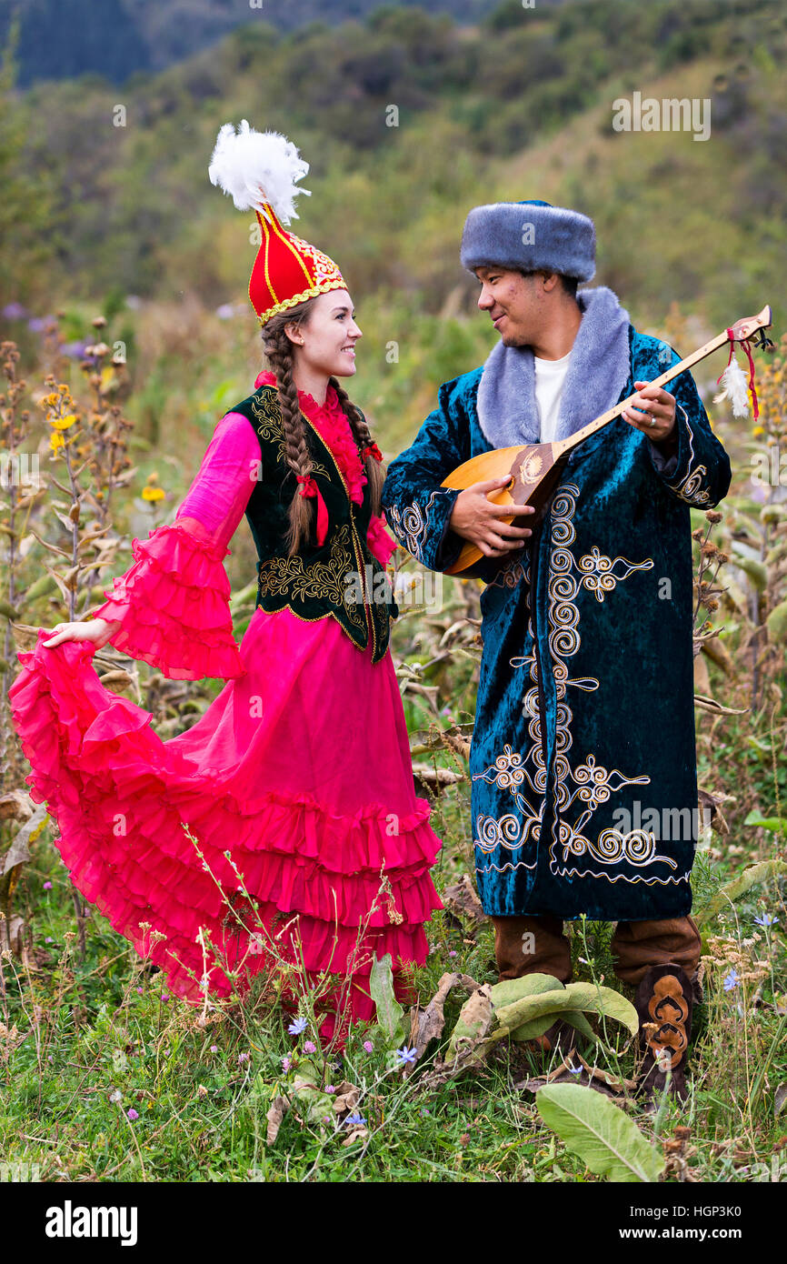 Couple kazakh en costumes nationaux avec homme jouant l'instrument de musique local de Dombra, Kazakhstan Banque D'Images