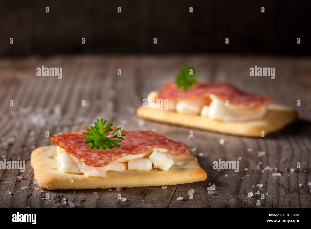 Cracker snacks avec square de salami et de fromage crème sur fond de bois Banque D'Images