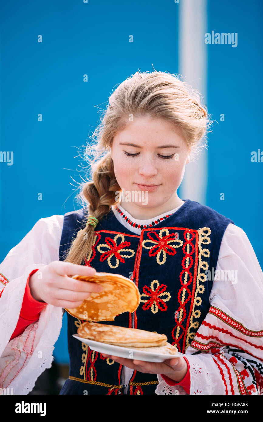 Gomel, Bélarus - 12 mars 2016 : Pas de belle jeune femme fille en vêtements folklorique national tente sur le goût des crêpes lors de célébration de Maslenitsa Shr Banque D'Images