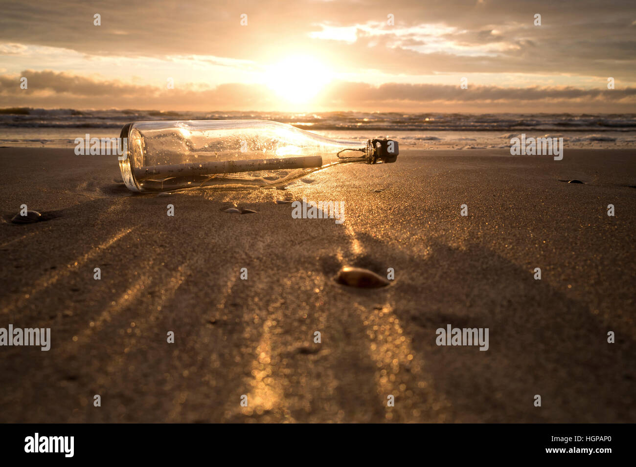 Message dans une bouteille échouée sur la plage au coucher du soleil Banque D'Images