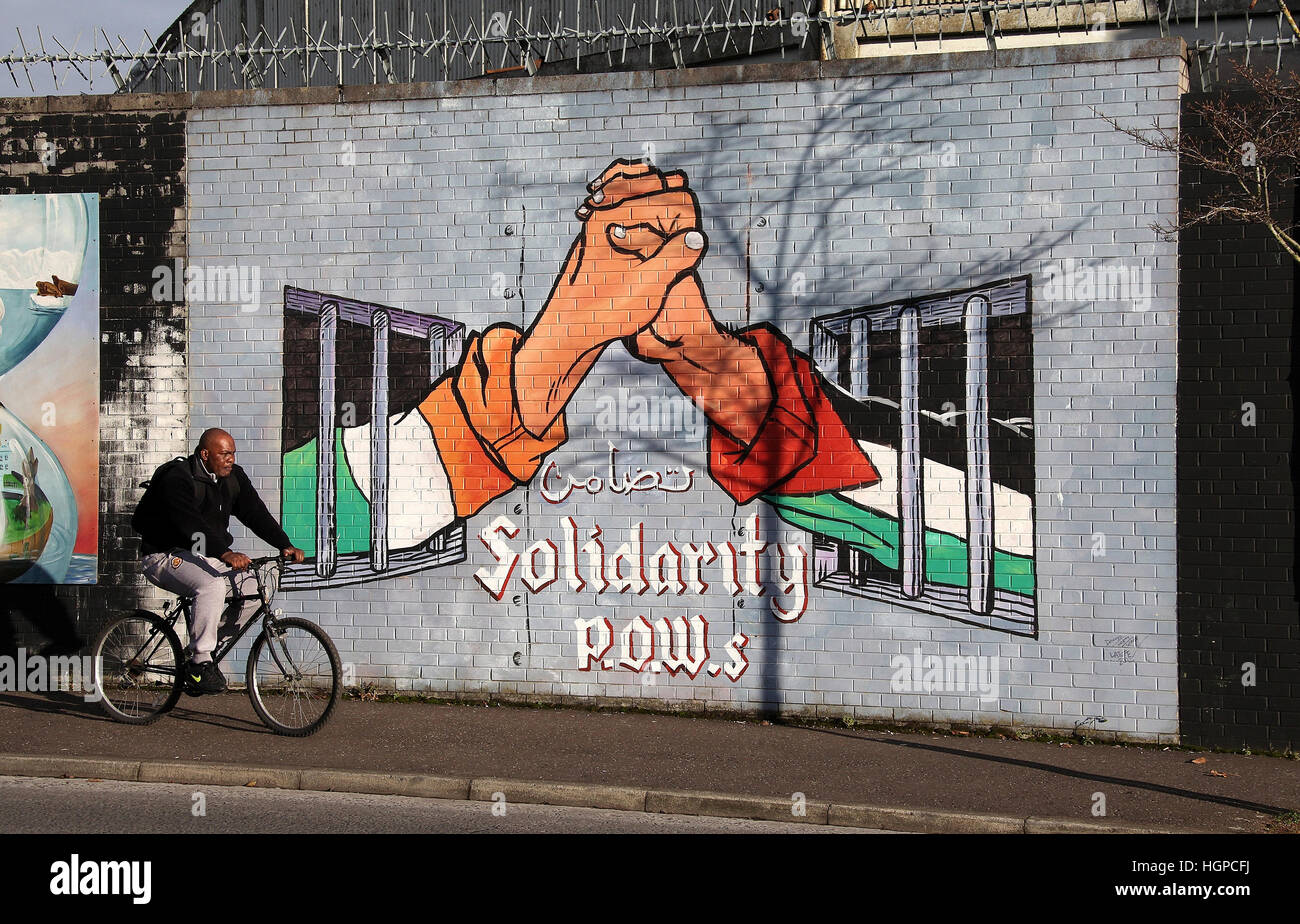 Vélo de l'homme en face de la paroi de la paix le long de la rue Northumberland Falls district de Belfast Banque D'Images