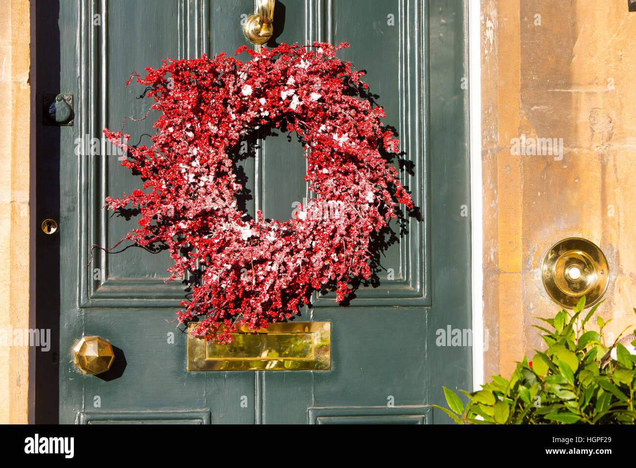Couronne de Noël rouge décore une porte dans la ville de Chipping Campden dans les Cotswolds, Gloucestershire, Angleterre Banque D'Images