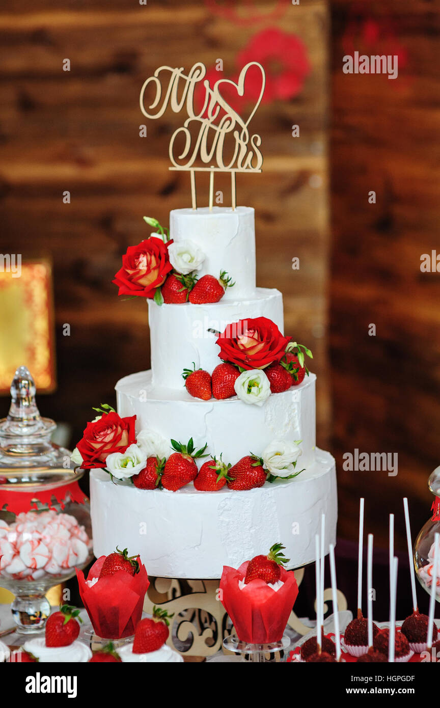 Belle trois couches de gâteau de mariage décoré avec les fleurs rouges Banque D'Images