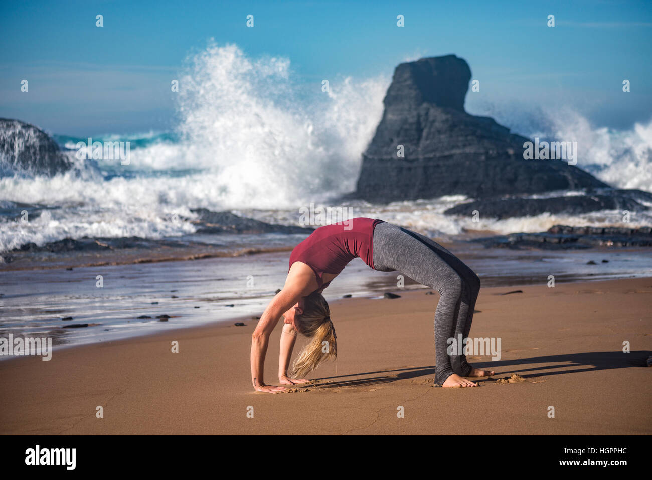 Une femme faisant du yoga à la plage Banque D'Images