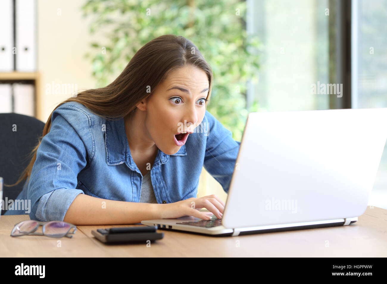 Entrepreneur étonné travaillant sur ligne avec un laptop at office Banque D'Images