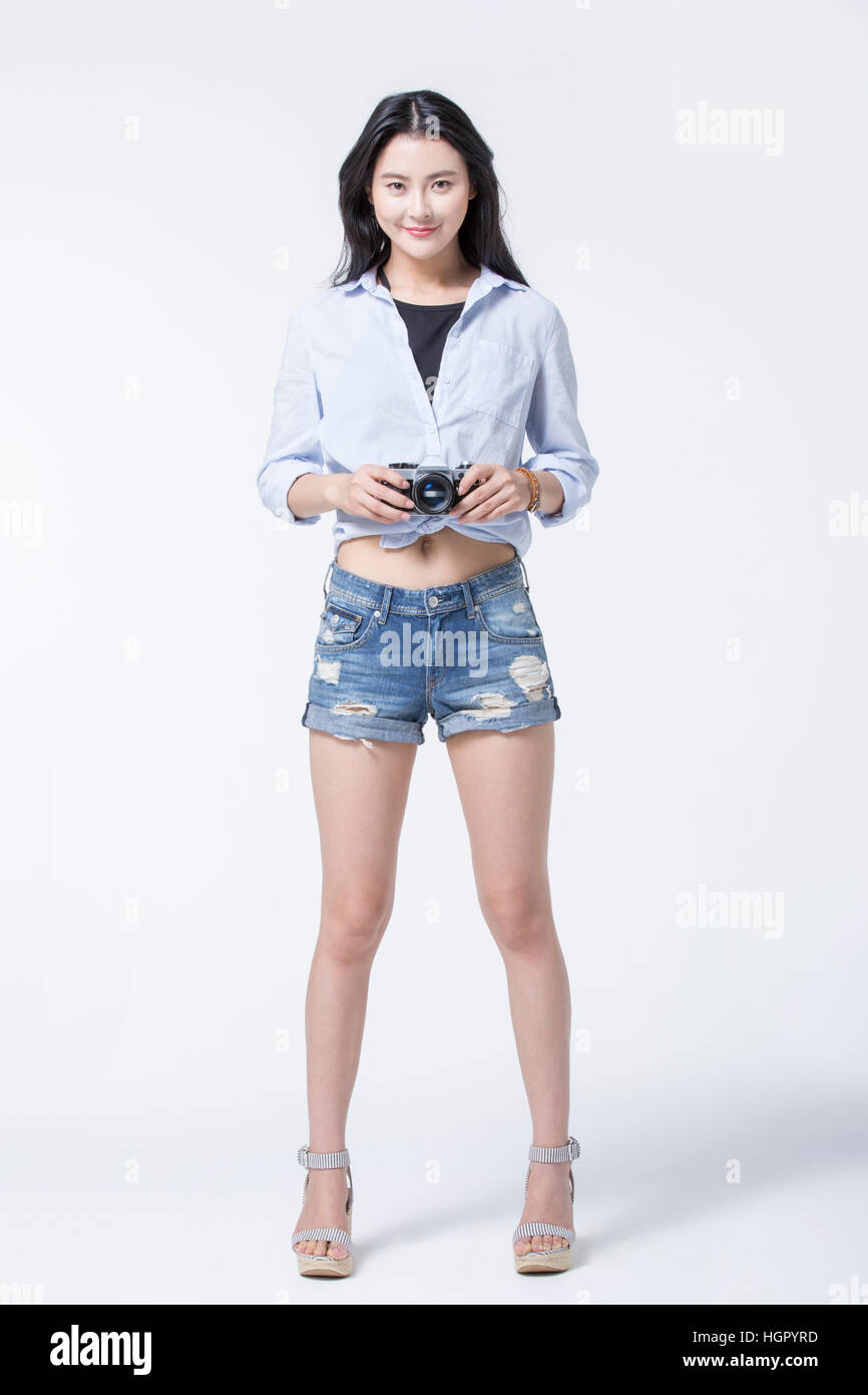 Young smiling woman in casual clothes posing with a camera Banque D'Images