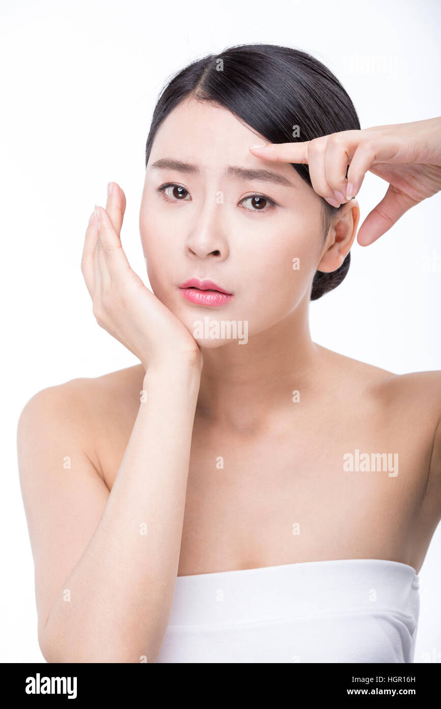Portrait de jeune femme en fronçant son visage de toucher sa peau Banque D'Images
