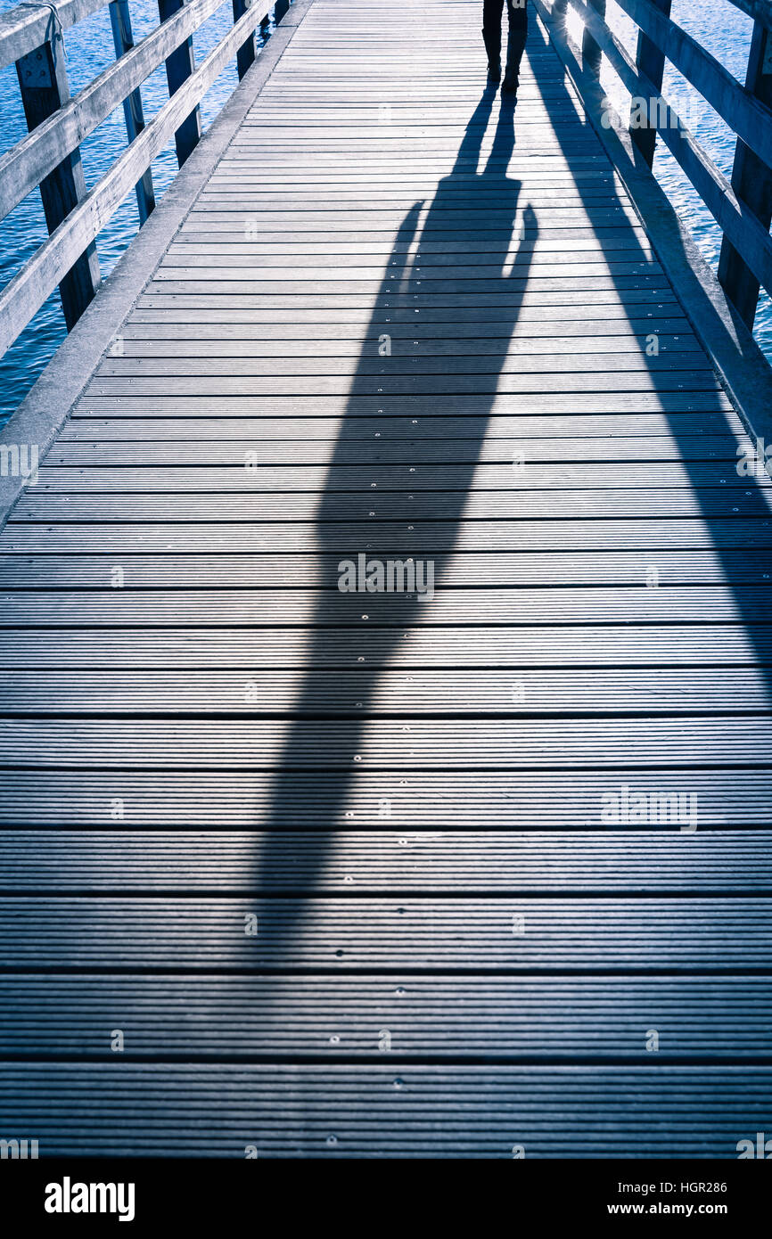 L'ombre de tout le corps silhouette de femme vu avec les chaussures marche  à bandes de jetée en bois au-dessus de la mer Photo Stock - Alamy