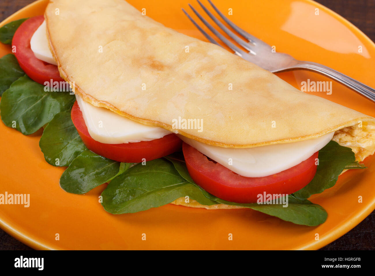Crepioca - pancake du manioc (tapioca) avec tomates, roquette (aragula) et le fromage sur la plaque sur fond de bois. Selective focus Banque D'Images