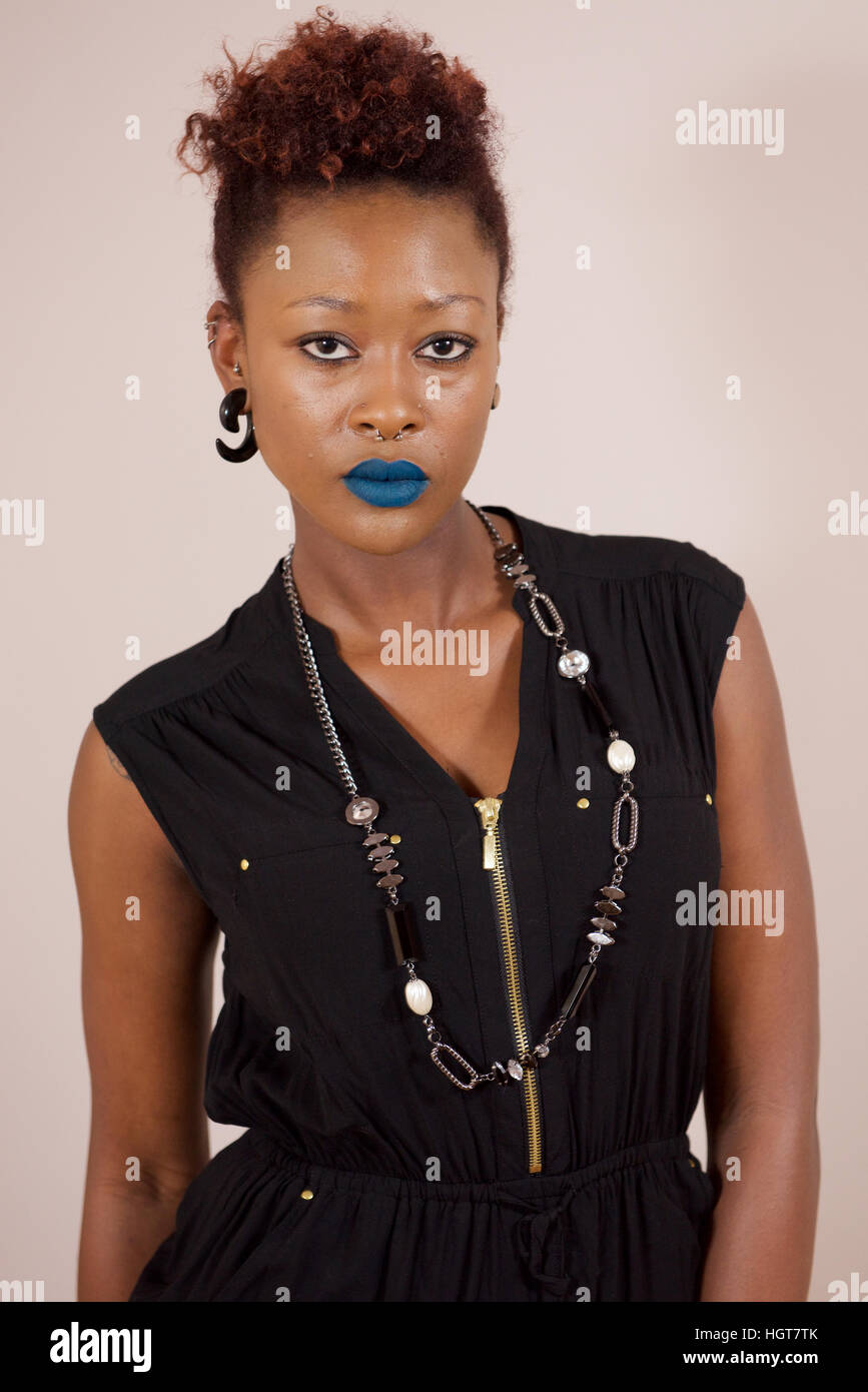 Belle jeune femme africaine dans un costume noir avec rouge à lèvres bleu. Banque D'Images