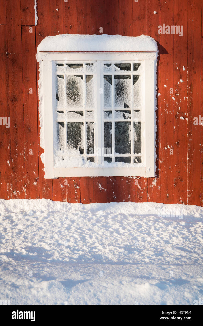 Vieux frosty fenêtre sur un mur rouge avec la neige. Roslagen, Suède, Scandinavie. Banque D'Images