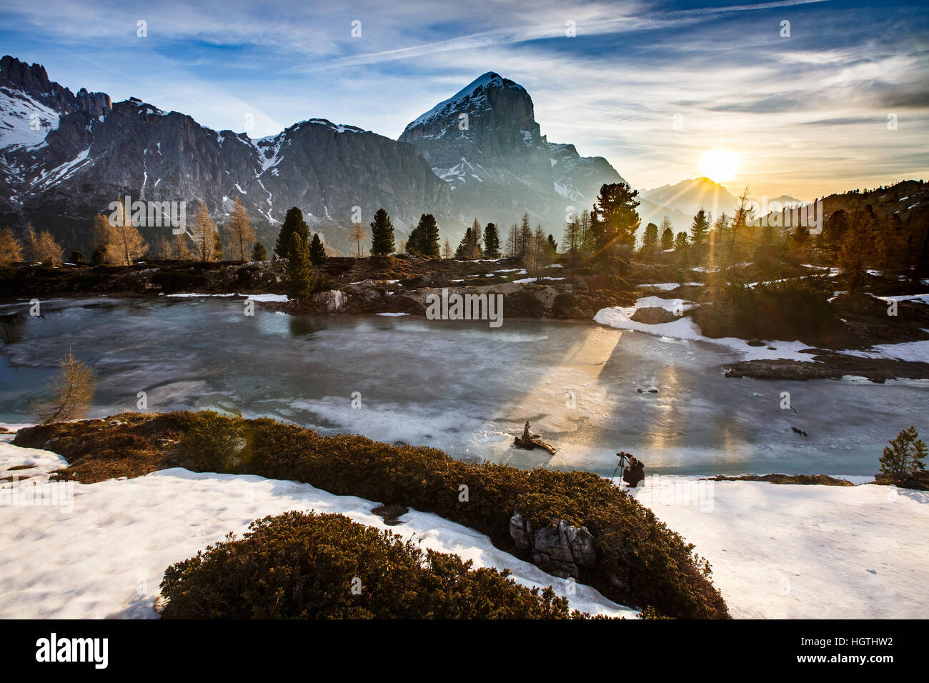 Paysage de montagne d'hiver avec lac gelé à l'avant et ciel dramatique de soleil du soir dans l'arrière-plan, du soleil qui sort des arbres. Désert, matières n Banque D'Images