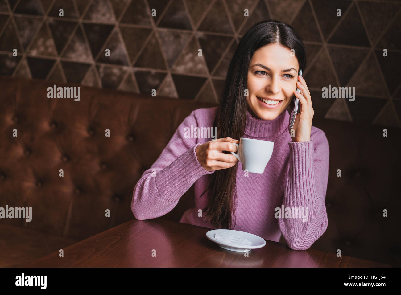 Jeune femme cheveux longs attrayants à l'aide de smart phone while sitting at coffee shop Banque D'Images