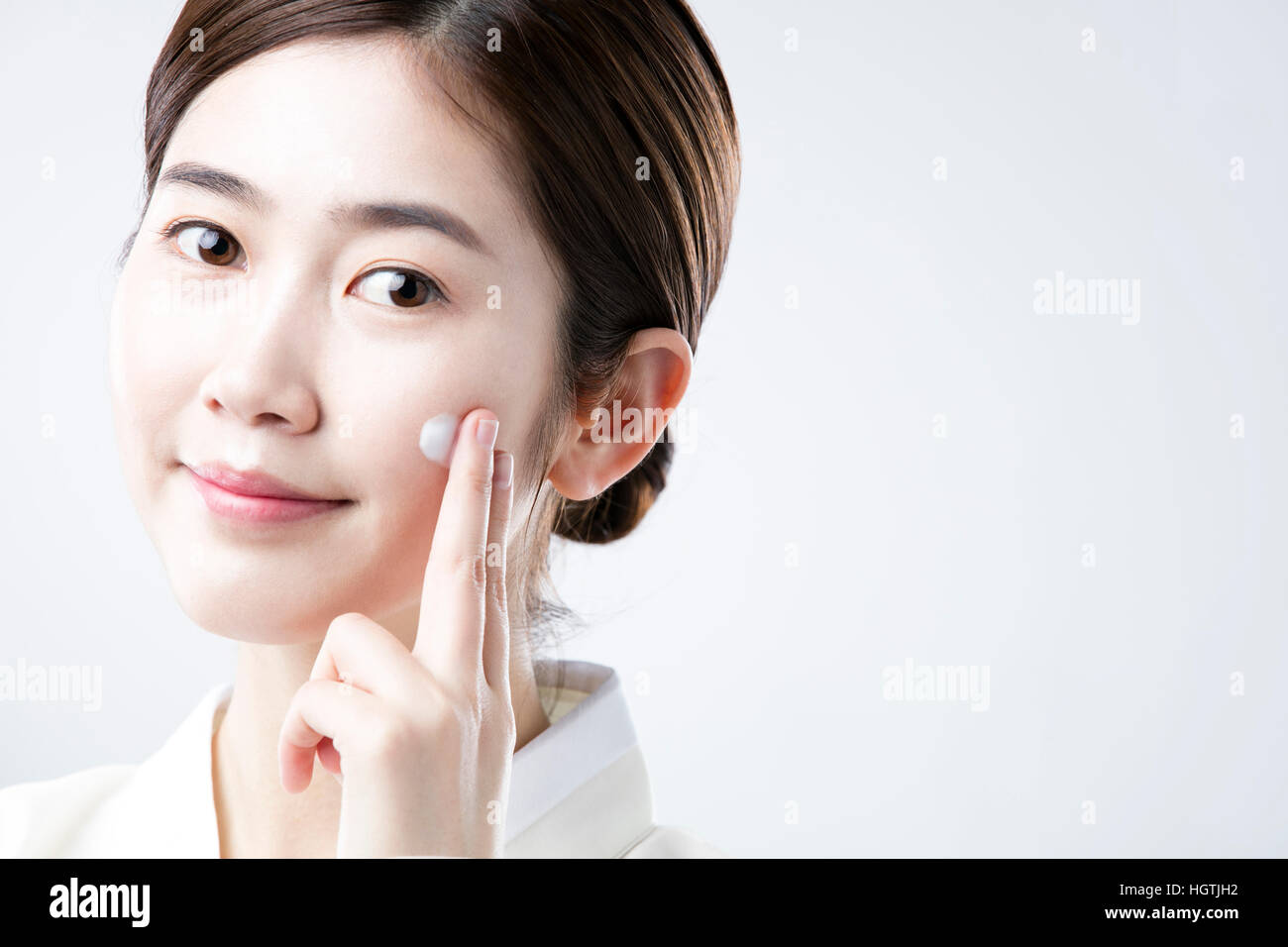 Portrait de jeune femme en vêtements traditionnels coréens, l'application de la crème sur sa joue Banque D'Images