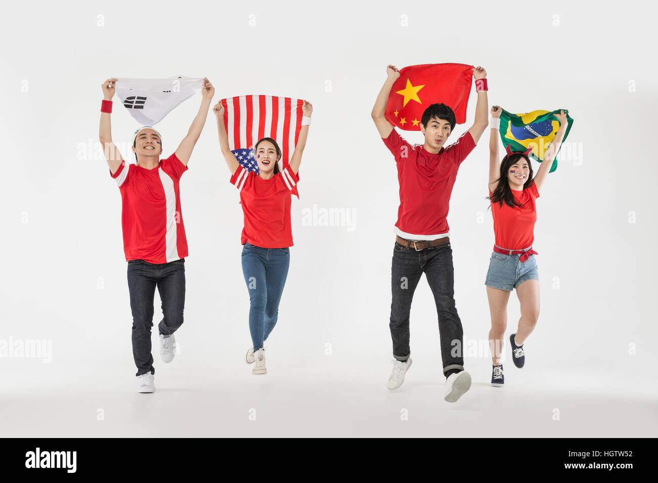 Young smiling cheerleaders exécutant holding drapeaux nationaux Banque D'Images