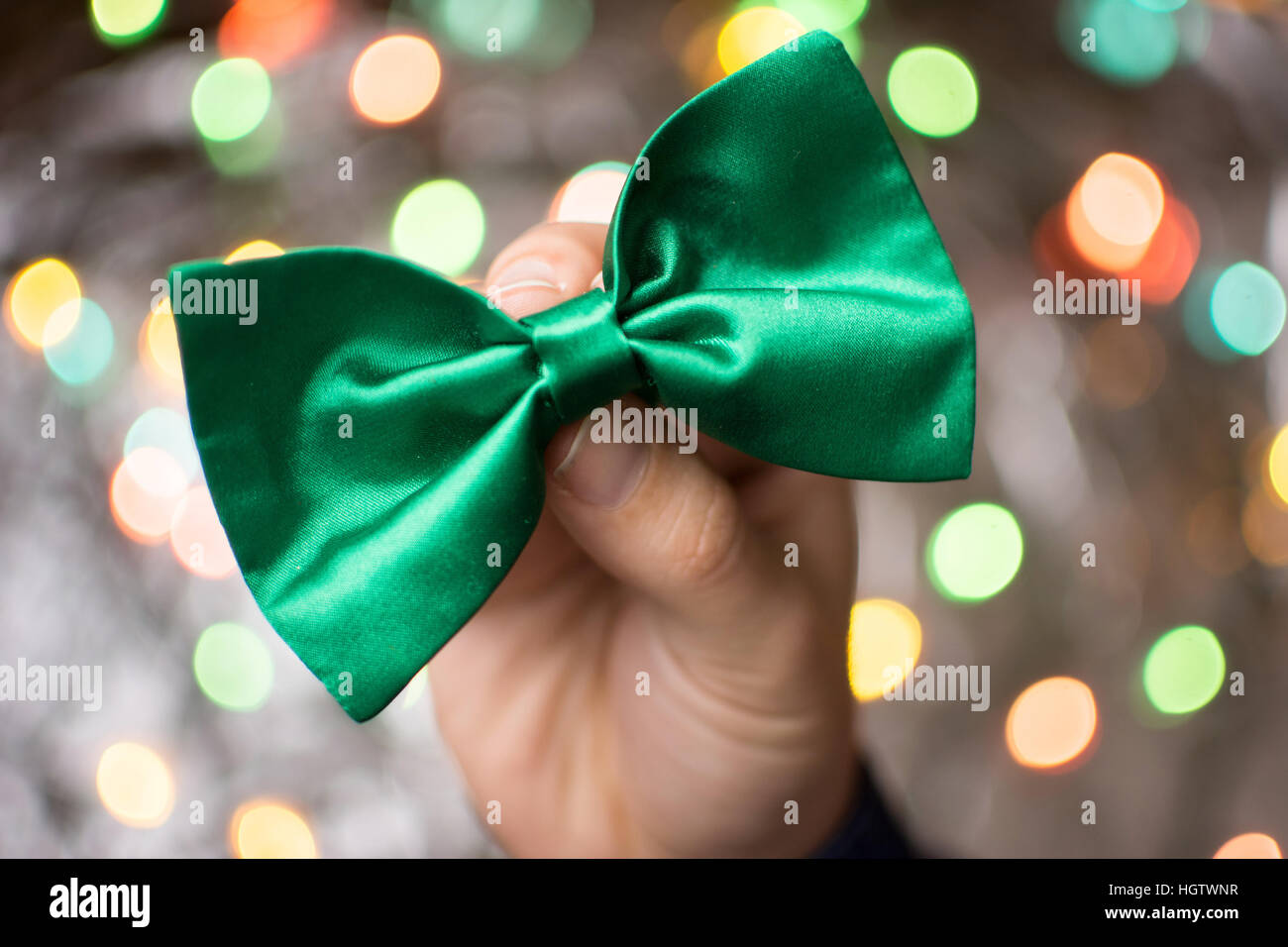 Male hand holding a green Bow tie. Préparation St Patricks day Banque D'Images