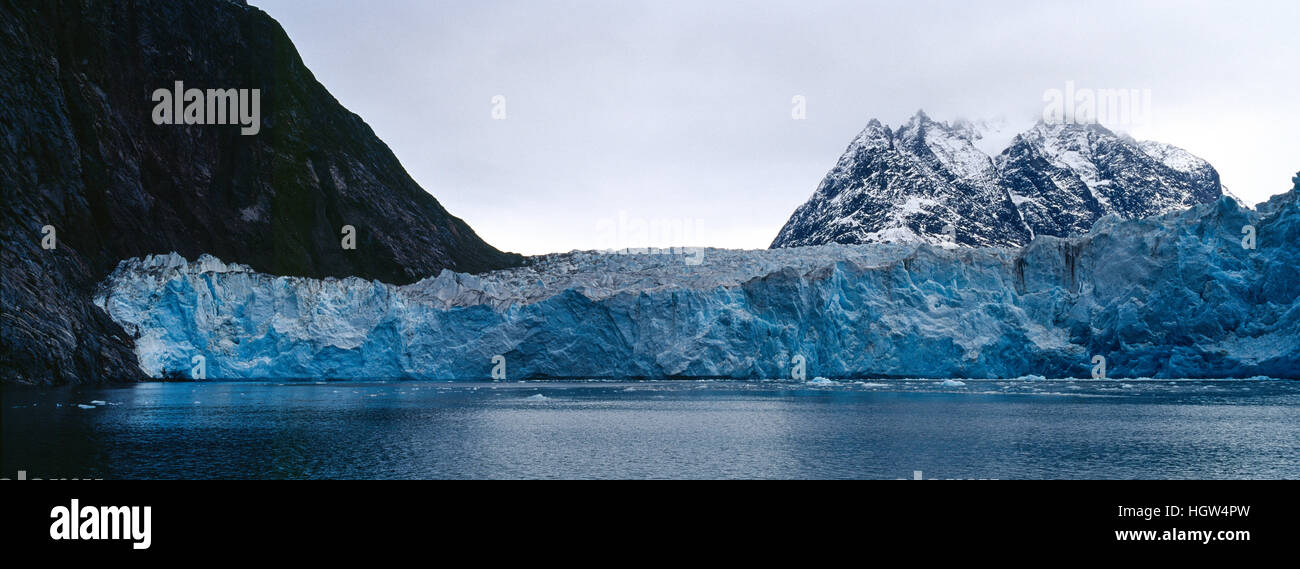 La zone de fracture pure d'un glacier en sandwich entre des sommets alpins dans un fjord. Banque D'Images