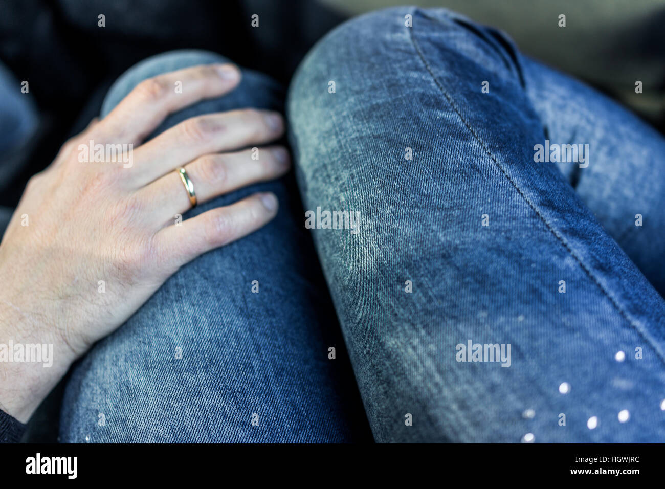 La main de l'homme avec l'anneau de mariage sur les jambes de la femme en  jeans dans Photo Stock - Alamy