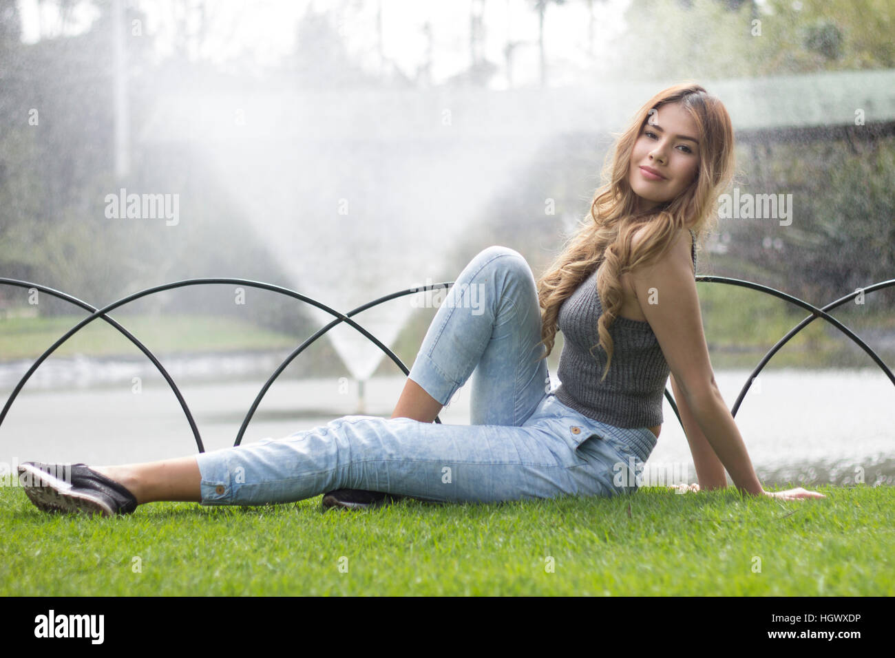 Jeune fille avec une fontaine d'eau derrière Banque D'Images