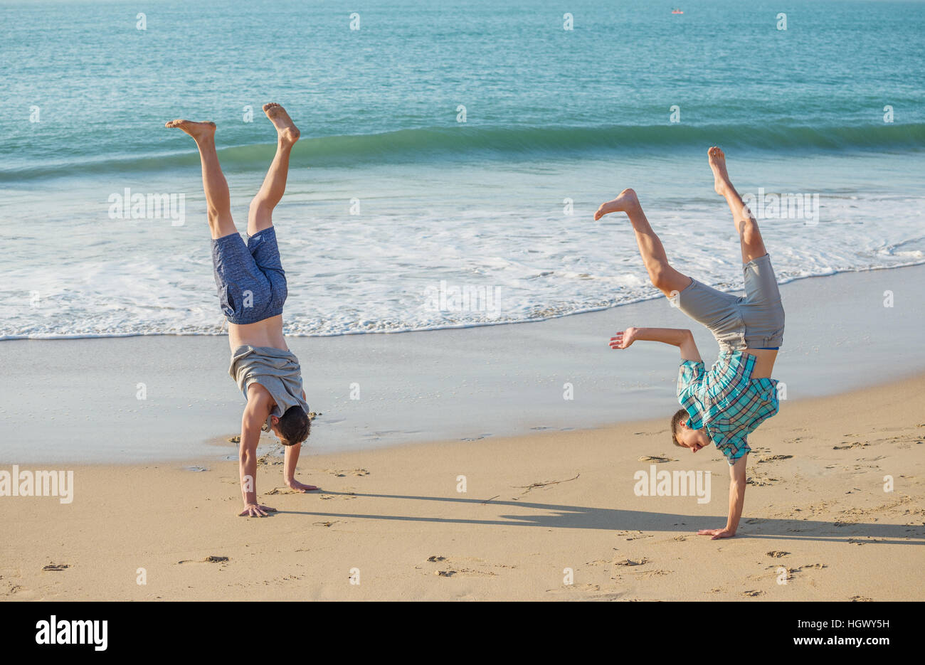 Deux jeunes hommes s'amuser sur la plage, dans la lumière du soir. Banque D'Images