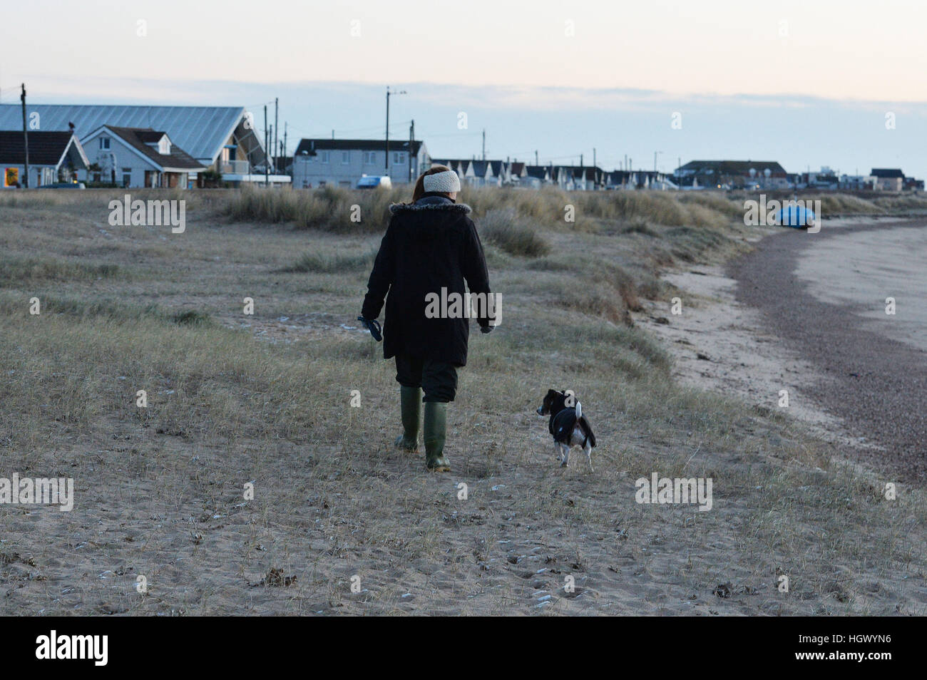 Un résident de son chien promenades sur la plage à Jaywick, Essex, d'où la police est l'évacuation de résidents au milieu les craintes d'inondations causées par un raz-de-marée plus tard cet après-midi. Banque D'Images