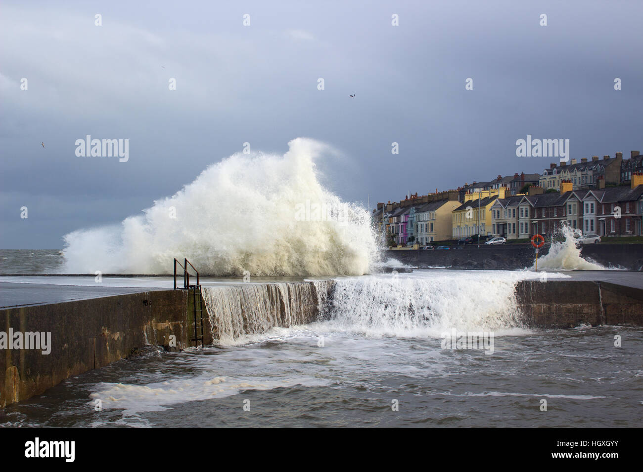 Une tempête hivernale buffet la mur du port de l'envoi et de pulvérisation de mousse des vagues dans l'air et rideaux d'eau dans la mer en cascade Banque D'Images