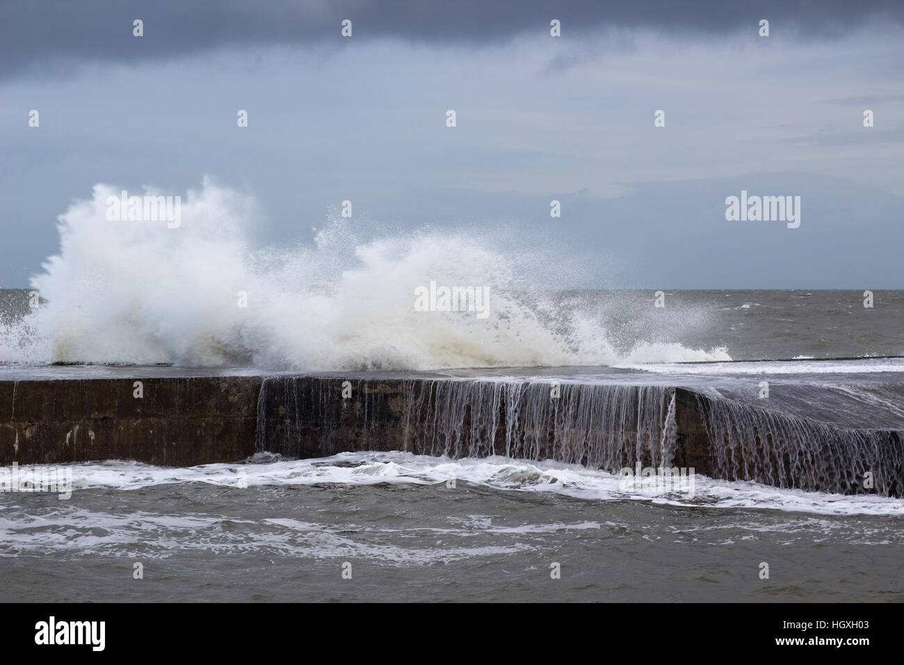 Une tempête hivernale buffet la mur du port de l'envoi et de pulvérisation de mousse des vagues dans l'air et rideaux d'eau dans la mer en cascade Banque D'Images