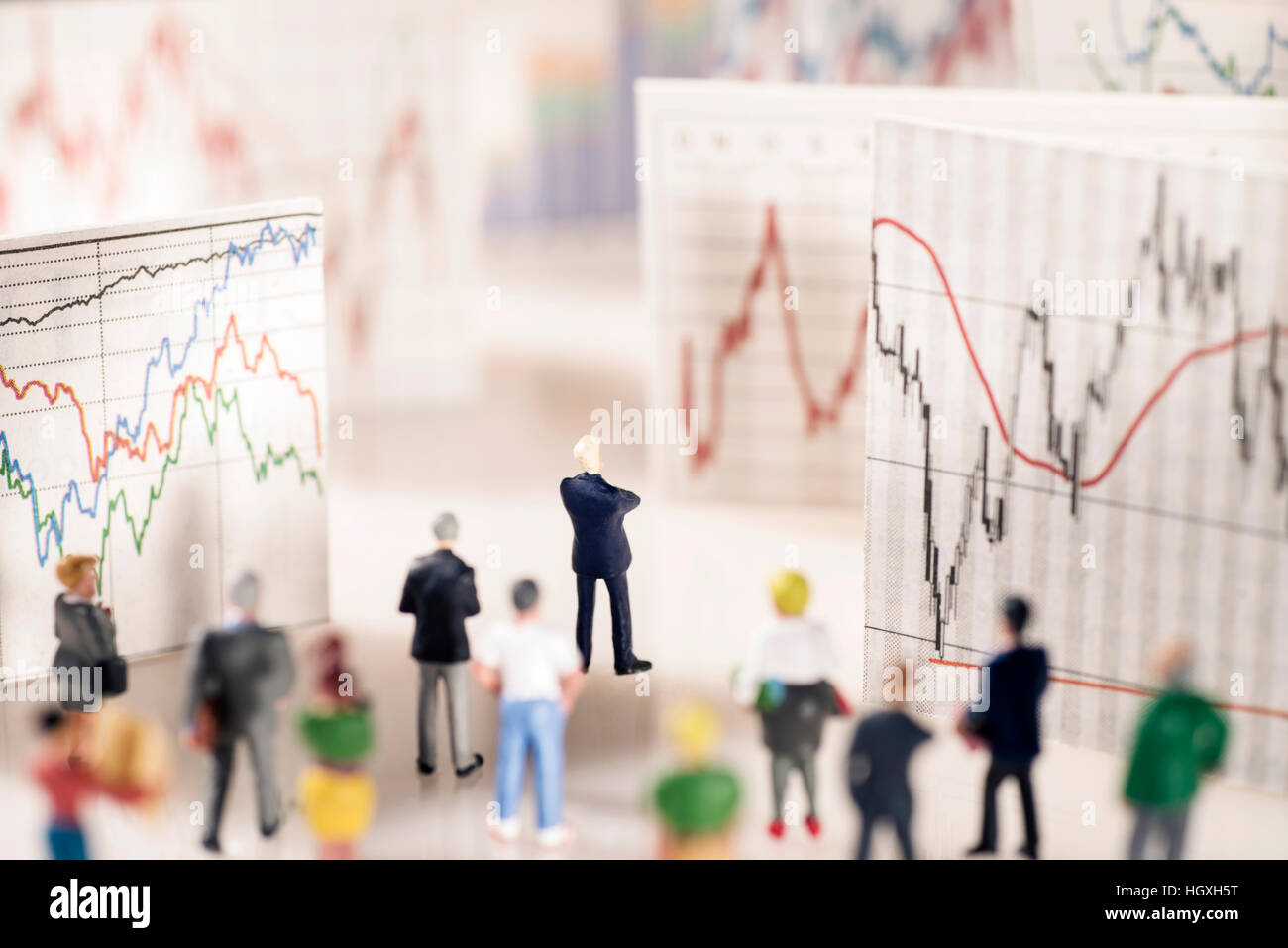 Banquier se tient sur un piédestal de pièces et regarde avec différents graphiques. Banque D'Images
