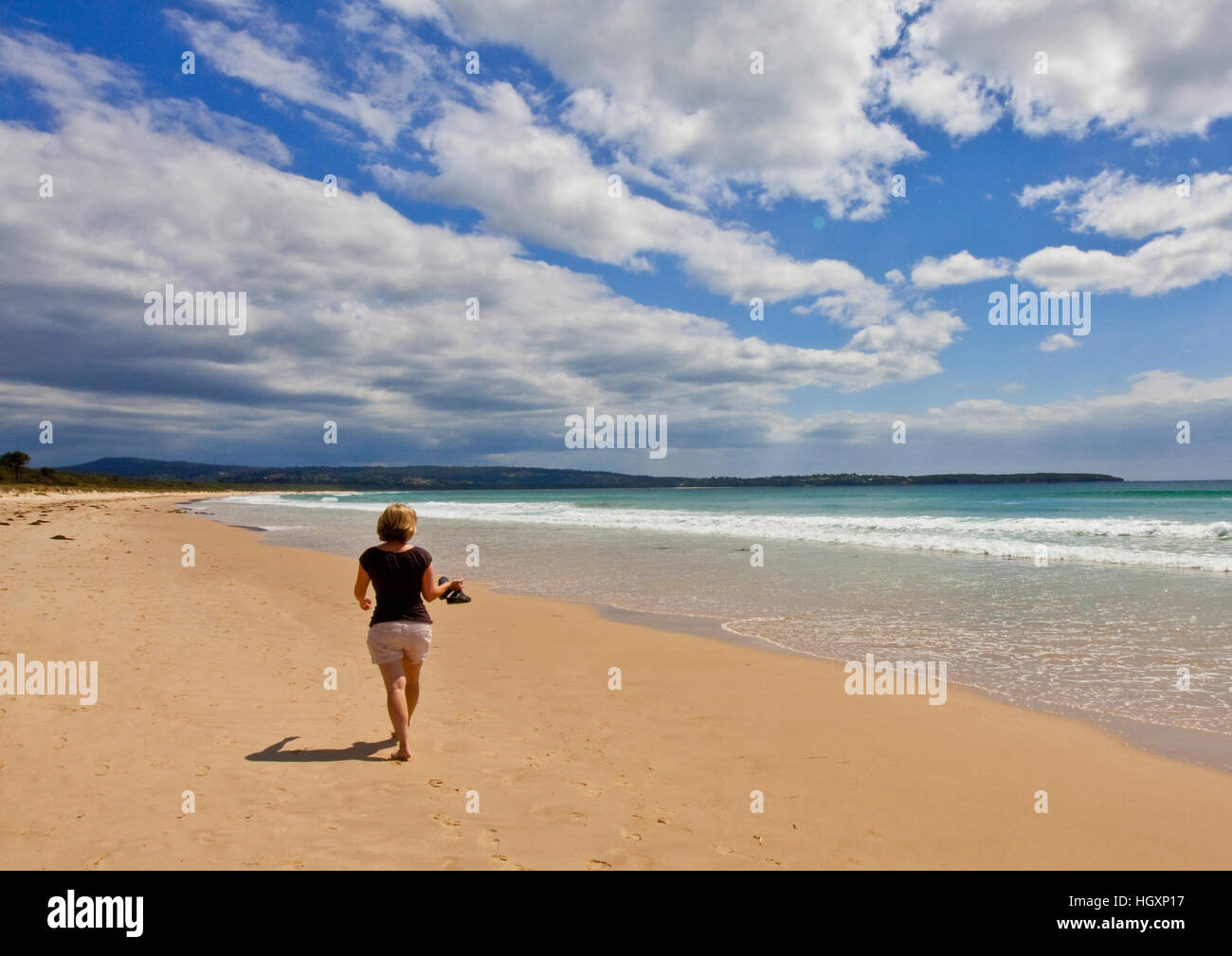 Jeune femme marche sur plage déserte Banque D'Images