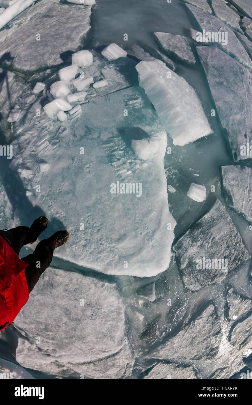 Vue de dessus d'un pied humain sur la glace est couverte de fissures et des buttes. Banque D'Images