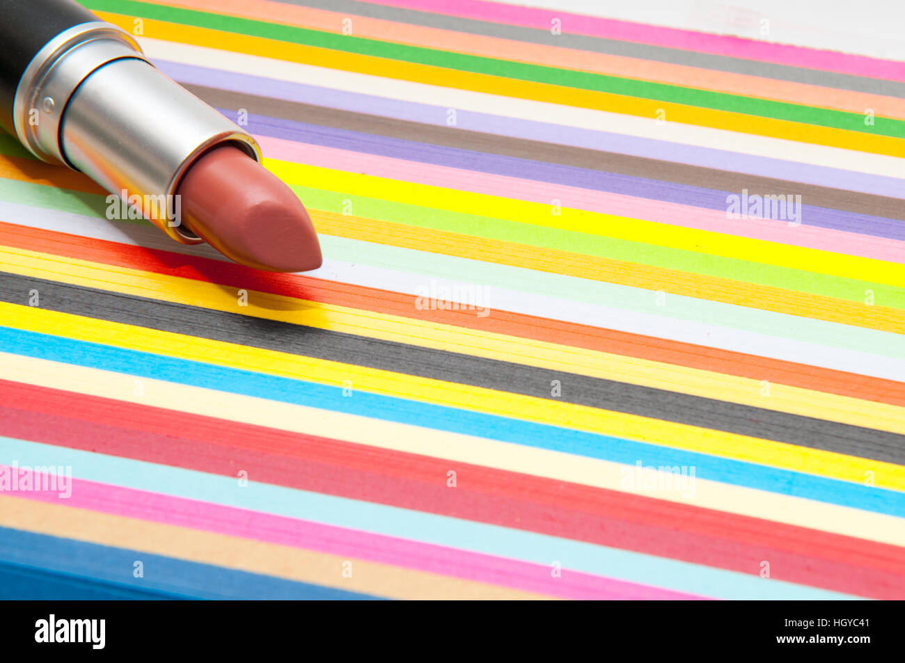 Produit cosmétique de rouge à lèvres sur un fond à rayures colorées lumineuses Banque D'Images