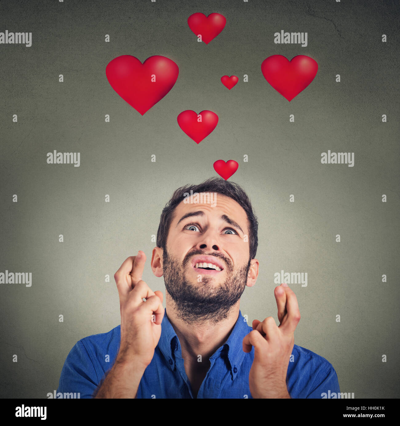 Jeune homme qui aime faire un souhait isolé sur fond gris avec coeur rouge audessus de la tête
