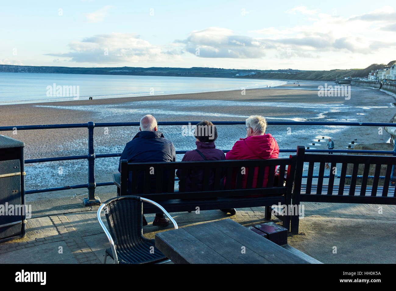 Trois personnes âgées assises sur un banc surplombant la plage de Filey, North Yorkshire Banque D'Images