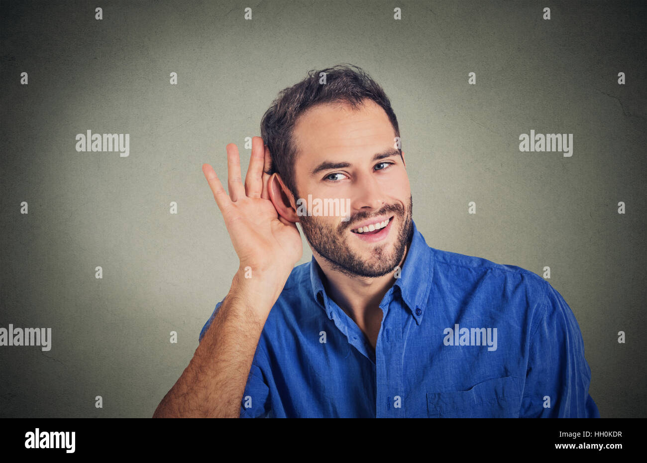 Beau jeune homme d'affaires de Nosy Be dans l'écoute en secret sur la conversation, part à l'oreille, souriant à potins juteux avec sourire sur le visage Banque D'Images