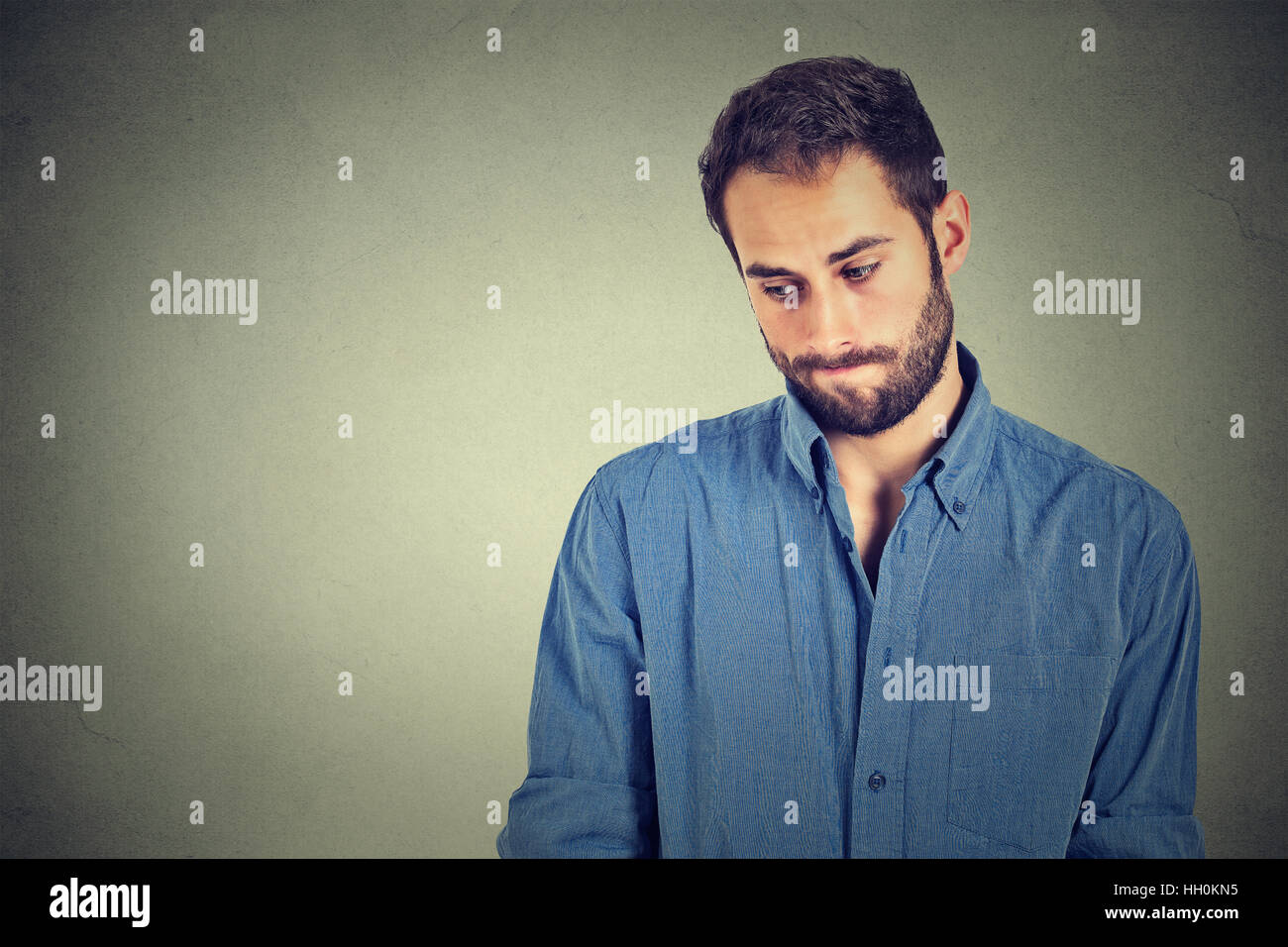 Manque de confiance. Bel homme jeune timide se sent isolé mur gris maladroit. L'émotion humaine la perception du langage corporel Banque D'Images