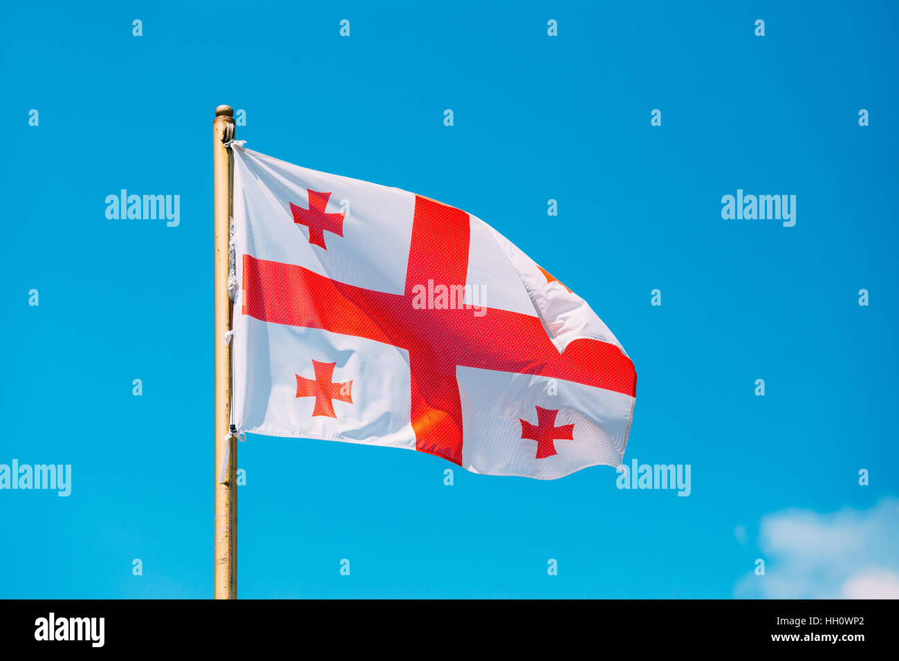 Fermer le drapeau de la Géorgie, cinq, agitant le drapeau sur mât au fond de ciel bleu ensoleillé. L'homme blanc et le symbole national, l'état civil et l'Etoile Banque D'Images