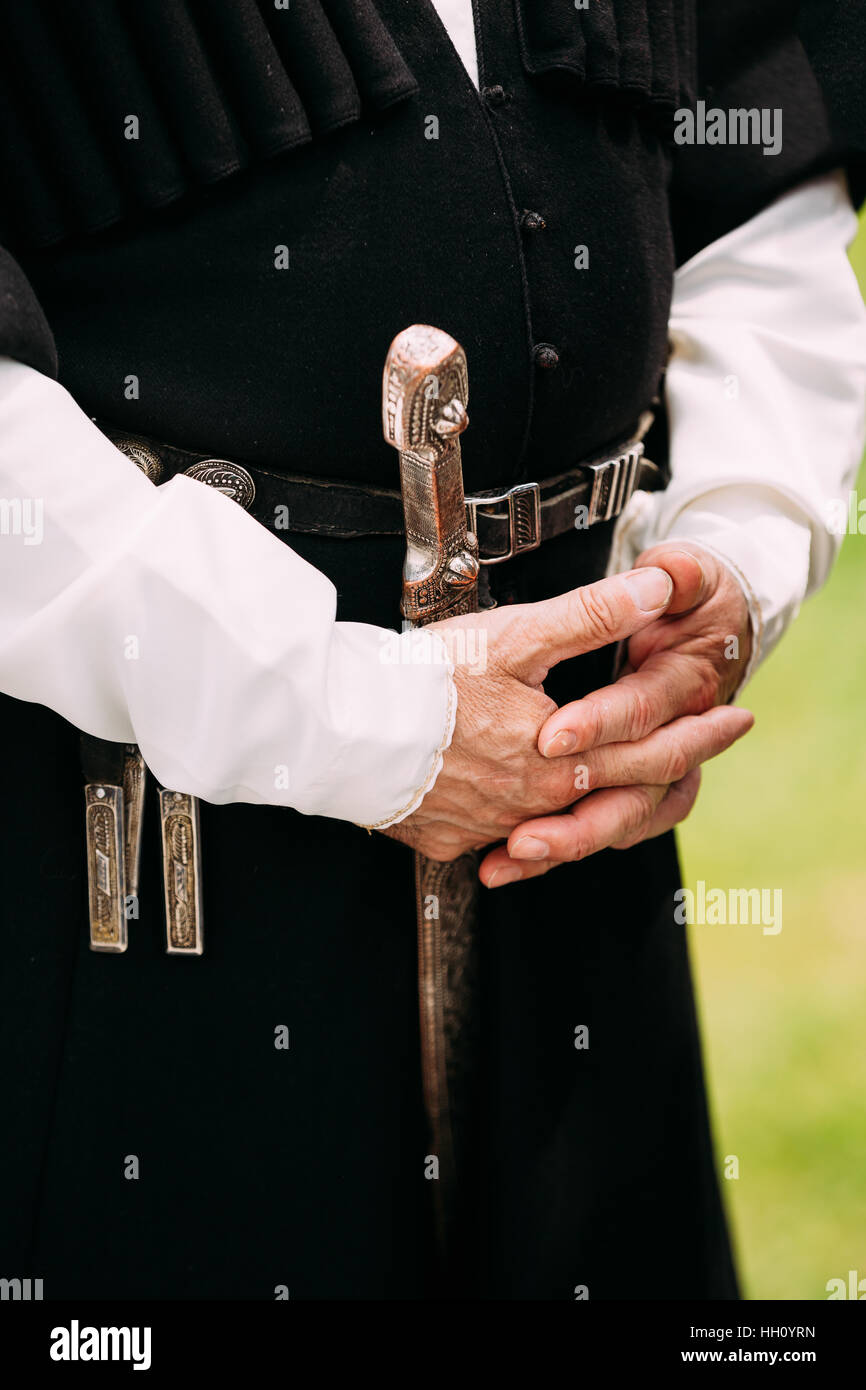 Close Up Hands d'ancien homme géorgien dans les vêtements. La culture de la Géorgie Pays. Dague à sa ceinture la pendaison. Ceinture d'argent avec une arme, un poignard Banque D'Images