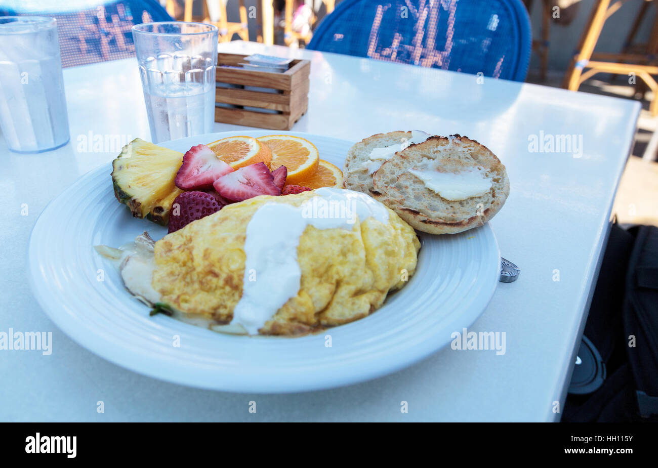 Petit-déjeuner omelette avec du fromage, un muffin anglais avec du beurre et des fruits, y compris l'ananas, les tranches d'orange et les fraises. Banque D'Images