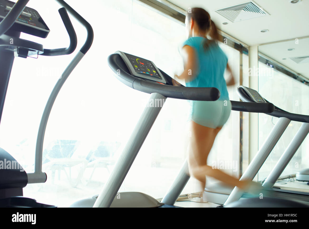 Young woman running on treadmill in gym Banque D'Images