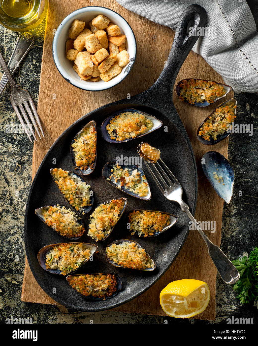 Les moules cuites au four délicieux sur un poêle de fer de chapelure, citron, persil, ail et huile d'olive. Banque D'Images