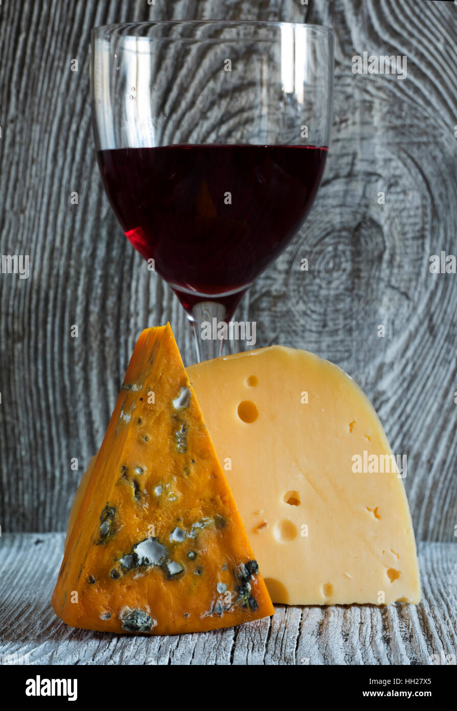 Des morceaux de fromage (roquefort, Maasdam) et du vin à l'ancienne en bois fond d'altération Banque D'Images