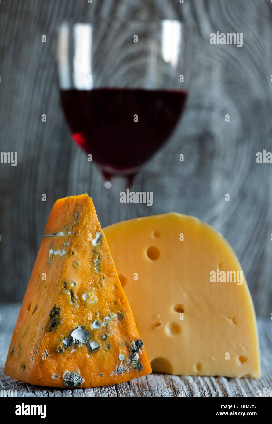 Des morceaux de fromage (roquefort, Maasdam) et du vin à l'ancienne en bois fond d'altération Banque D'Images
