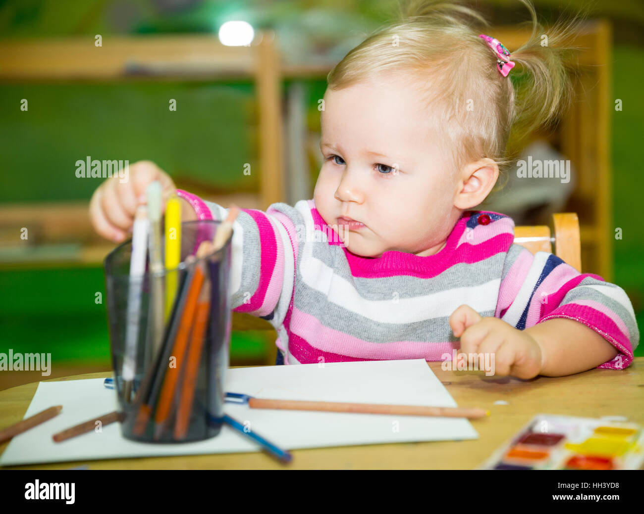 Adorable fille enfant dessin avec des crayons de couleur dans les prix. Au jardin d'enfants d'âge préscolaire Montessori en classe. Banque D'Images