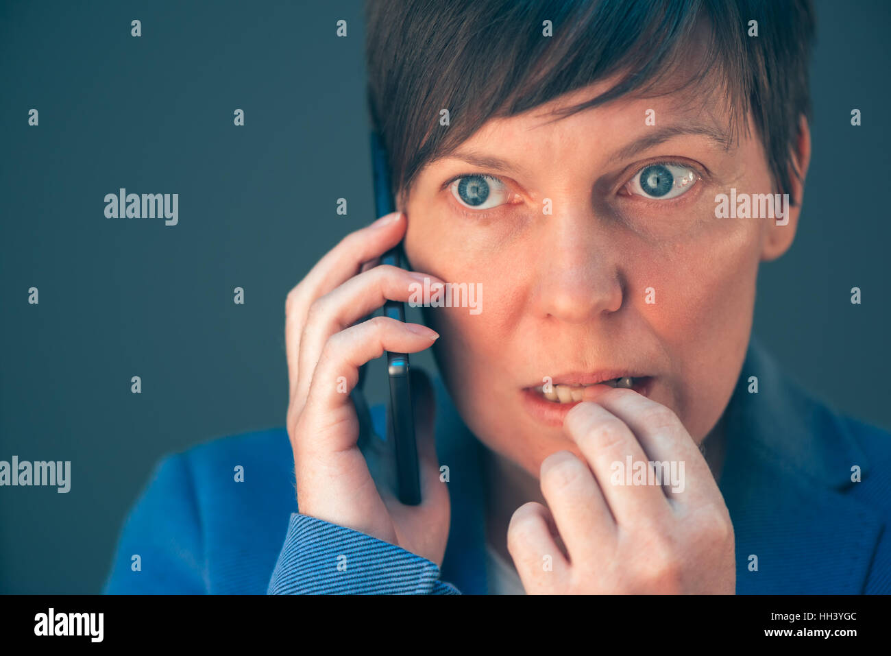 Femme d'nerveux ongles piqûres au cours de conversation téléphonique le téléphone mobile Banque D'Images