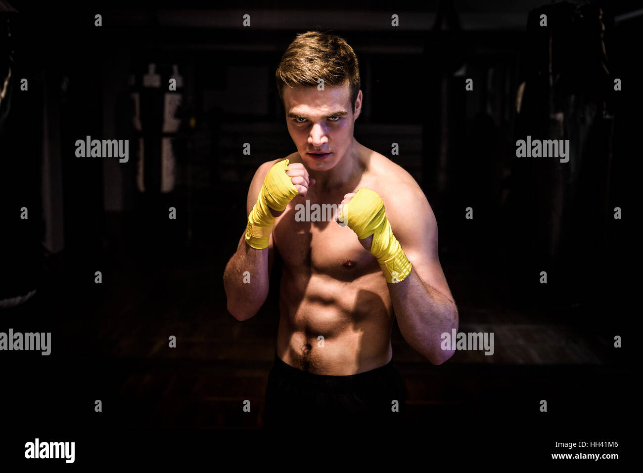 Street Fighter mma boxer avec bandages prêts pour fight club. Jeune homme athlétique ripped abs avec de gros et des roulés dans une salle de sport après une séance d'entraînement est de regarder kickbox Banque D'Images