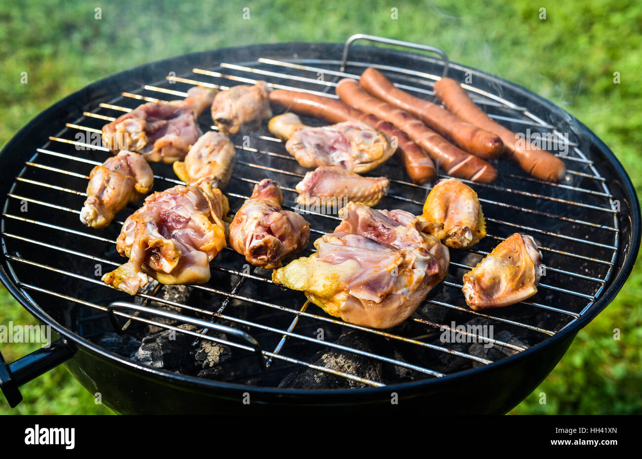 Délicieuse variété de viande sur le gril du barbecue à charbon char. La  cuisson des aliments sur un petit peu de type weber barbecue à la maison.  Saucisses, poulet, et chaud, ne