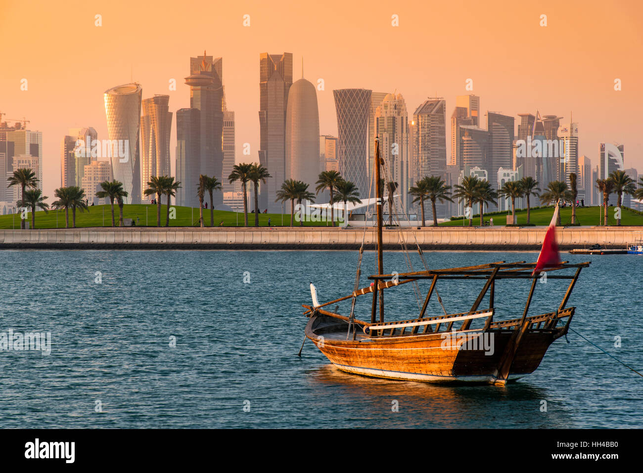 Bateau à voile traditionnel dhow avec le domaine financier derrière l'horizon au coucher du soleil, Doha, Qatar Banque D'Images